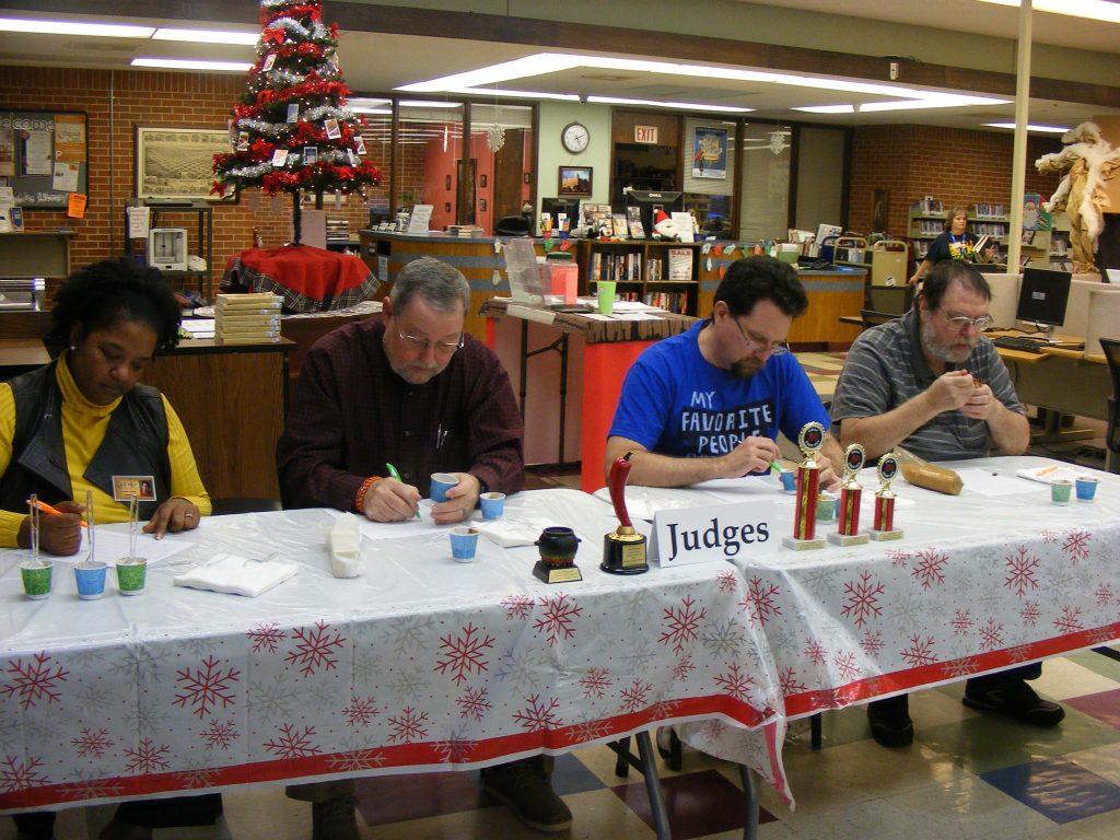 one woman and 3 men tasting chili aat the judges table. 