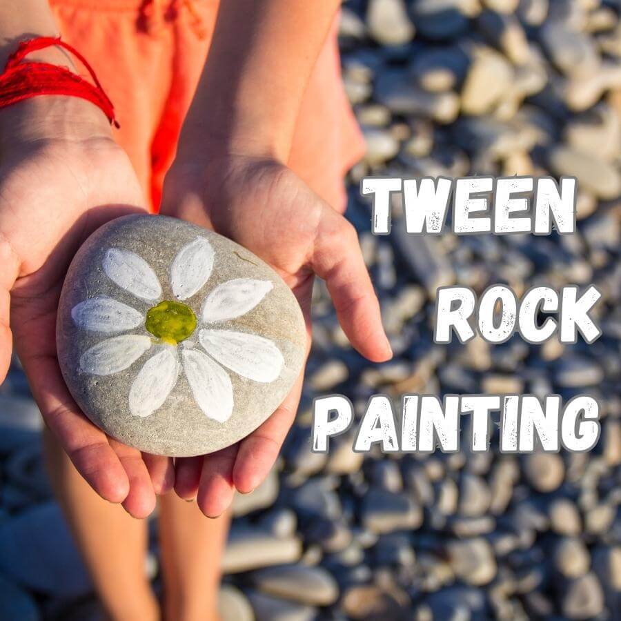 Child's hands hold a rock with a painted flower on it.